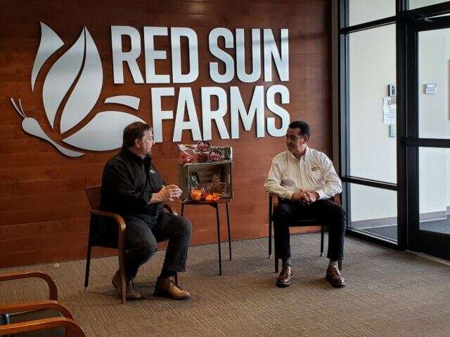 Chip sits with Red Sun Farms CEO Carlos Visconti.