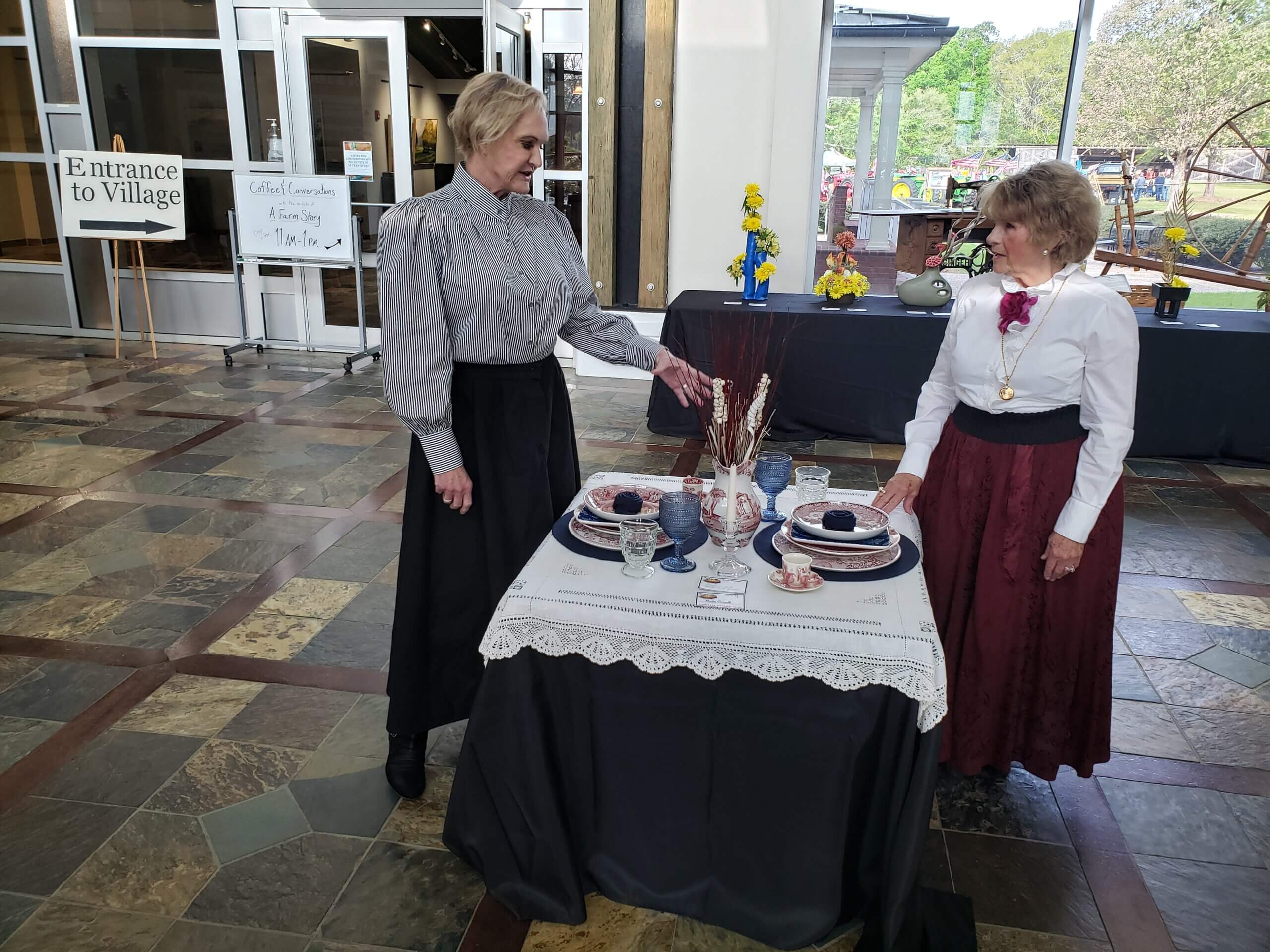 Women dressed from 1890's at a table with fine china.