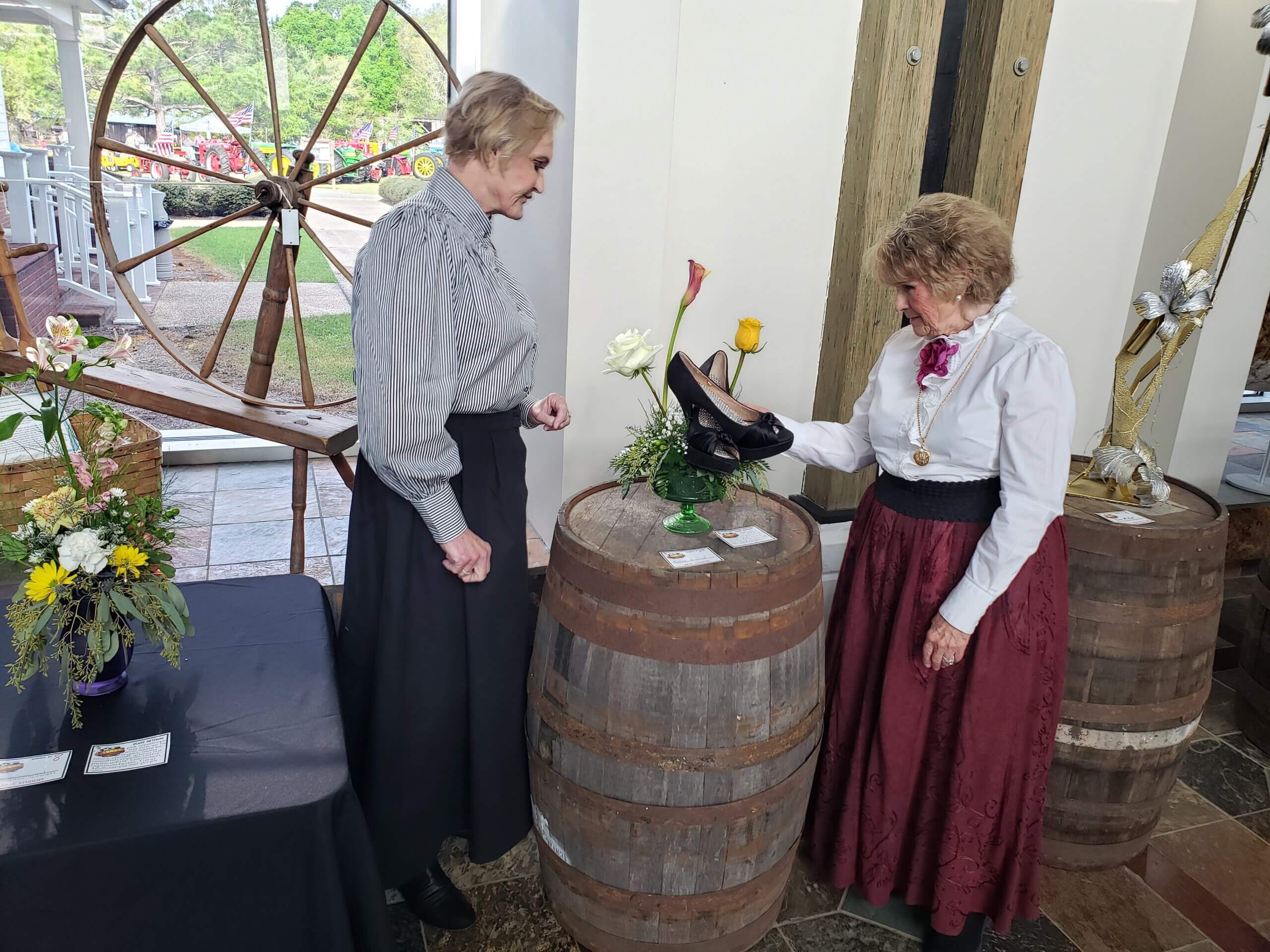 Women dressed from 1890's at a display of time-period shoes.