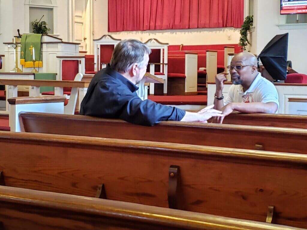 Host Chip Carter and Pastor Robert J. Yarbrough chat in the pews of St. Mark AMA Church.