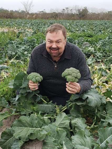 Chip holding two broccoli stalks he just picked. 