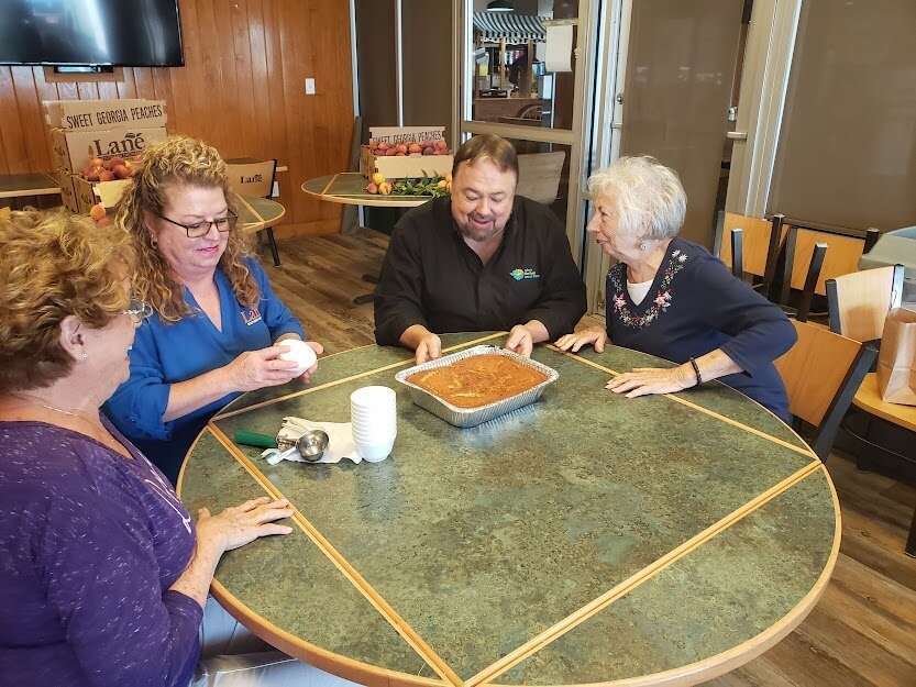 Vicky, Wendy, Chip & Jo laughing and having fun at table with a fresh peach cobbler from Lane Southern Orchard