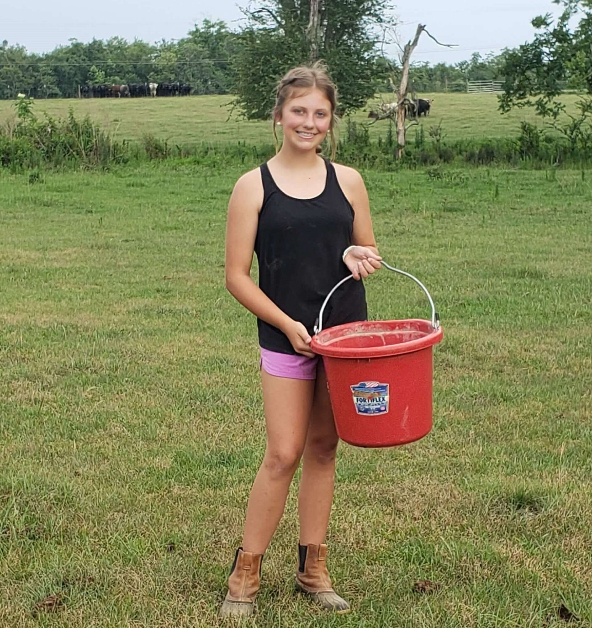 LizzyRae Gibbs holding a bucket of feed