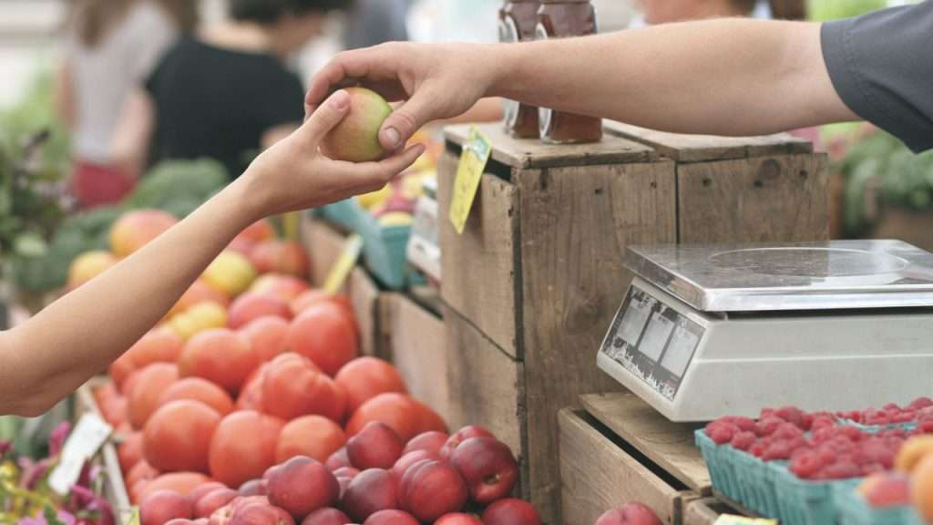 Clerk handing apple to customer.