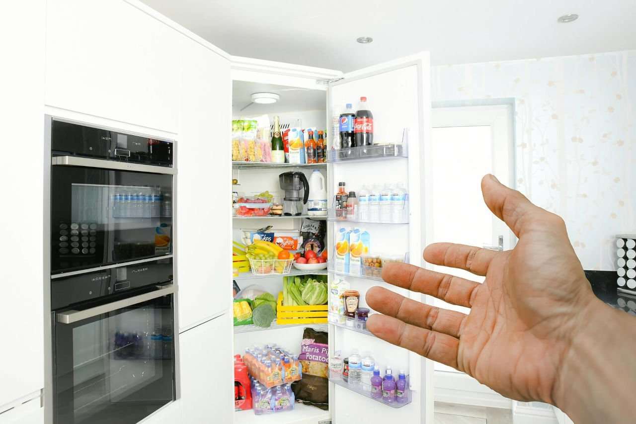 Person pointing to open refrigerator.