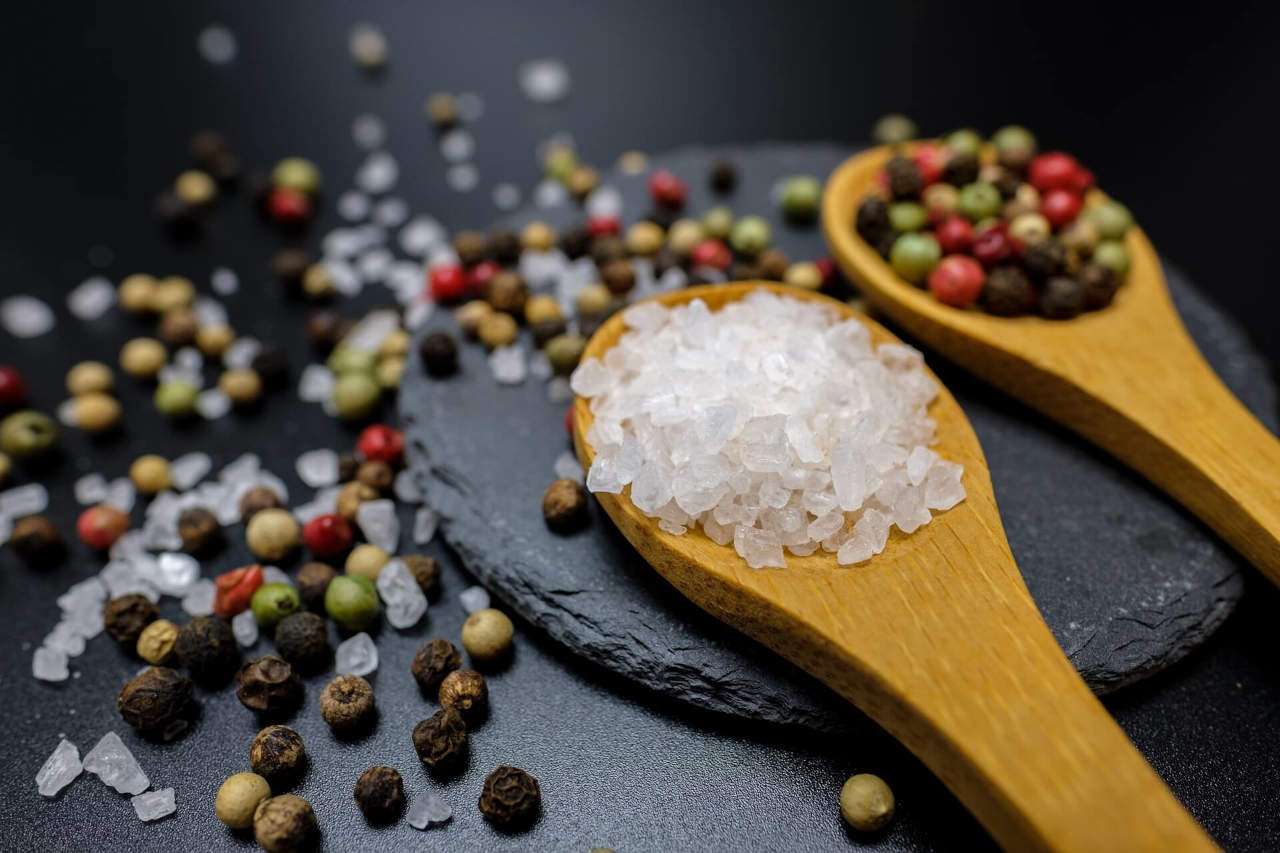 Salt and pepper corns on wood spoons.