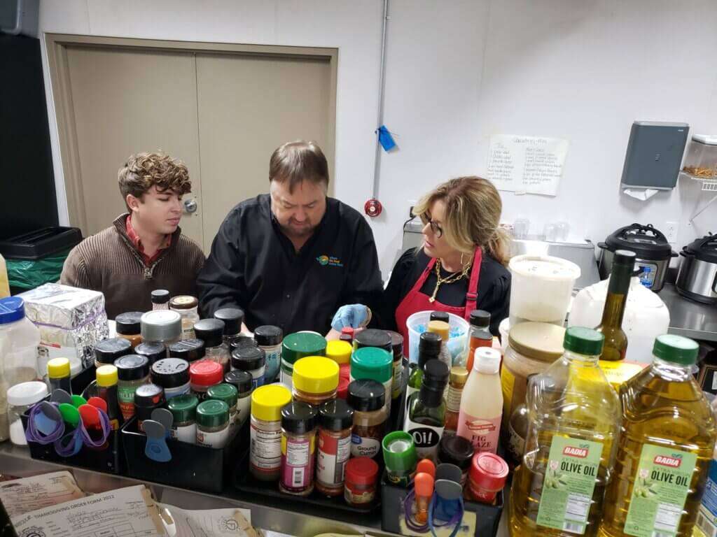 Three people in front of kitchen prep area.