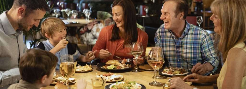 Family smiling and conversing at dinner.