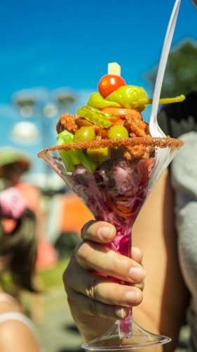 Fried chicken pieces in martini glass with onions, olives, and dressing.