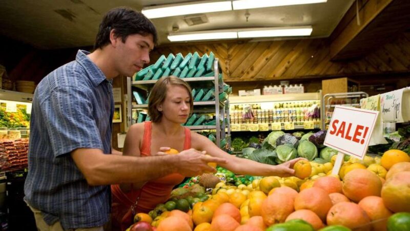 Two customers buying produce in a grocery store. Shopping, fruit. February 2010 IFAS Extension Calendar Image. Credit: Tyler Jones, UF/IFAS