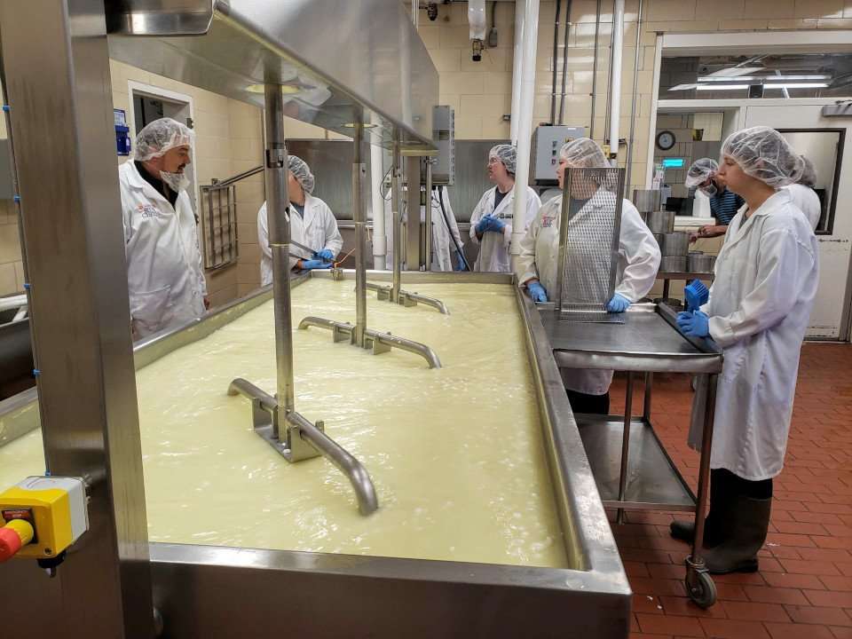 Clemson University student workers by milk vat.