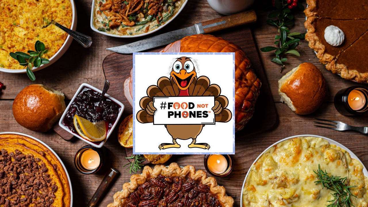 Thanksgiving dinner with cartoon turkey holding a "#FoodNotPhones" sign.