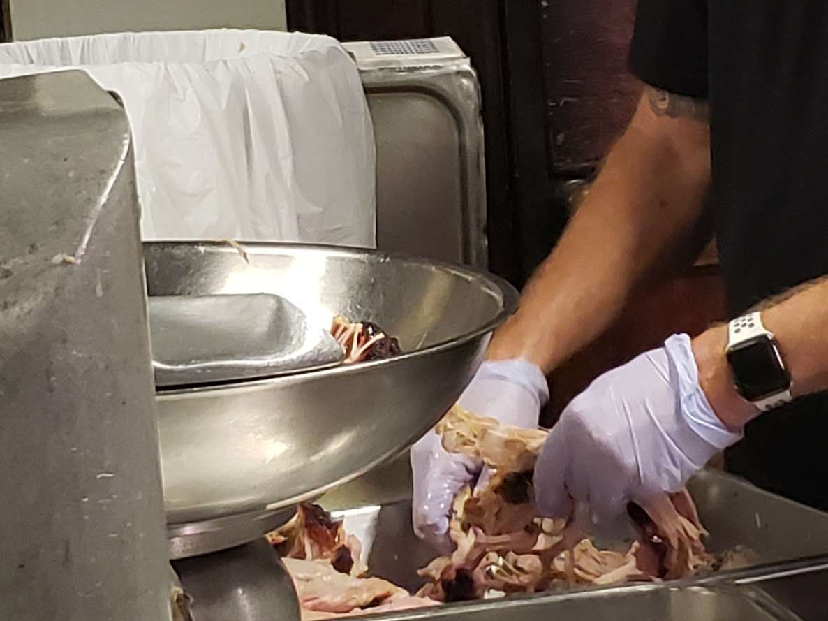 Hands with white gloves shredding meat