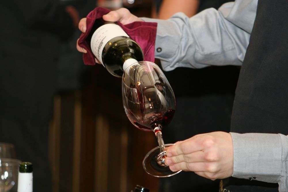 Waiter pouring a glass of red wine. 