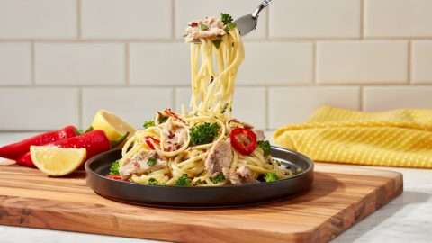 Season Brand lemon pasta with sardines in plate on cutting board.