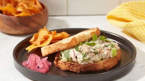 Season Brand sardine sandwich on plate with bread and chips.