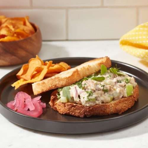 Season Brand sardine sandwich on plate with bread and chips.