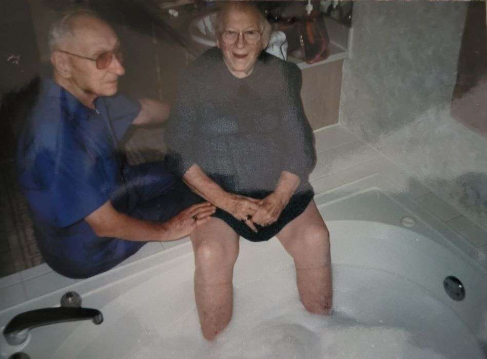 Mizz Frances sitting on top of tub soaking her feet. Granddaddy looking on.