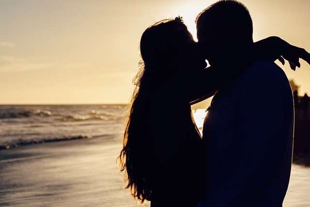 Silhouette of couple kissing on a beach.