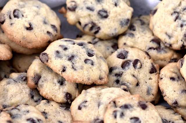 Stack of chocolate chip cookies in a silver bowl.