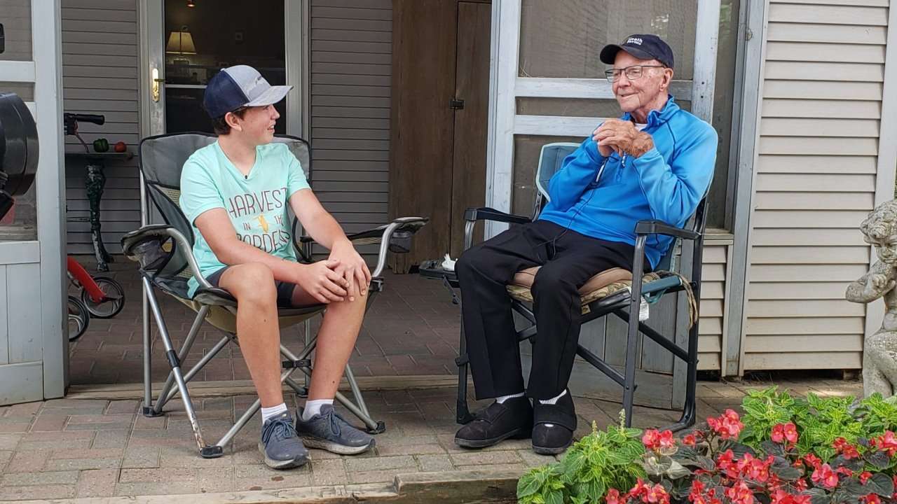 Weston Hannan and Bob Heath talking on front porch.