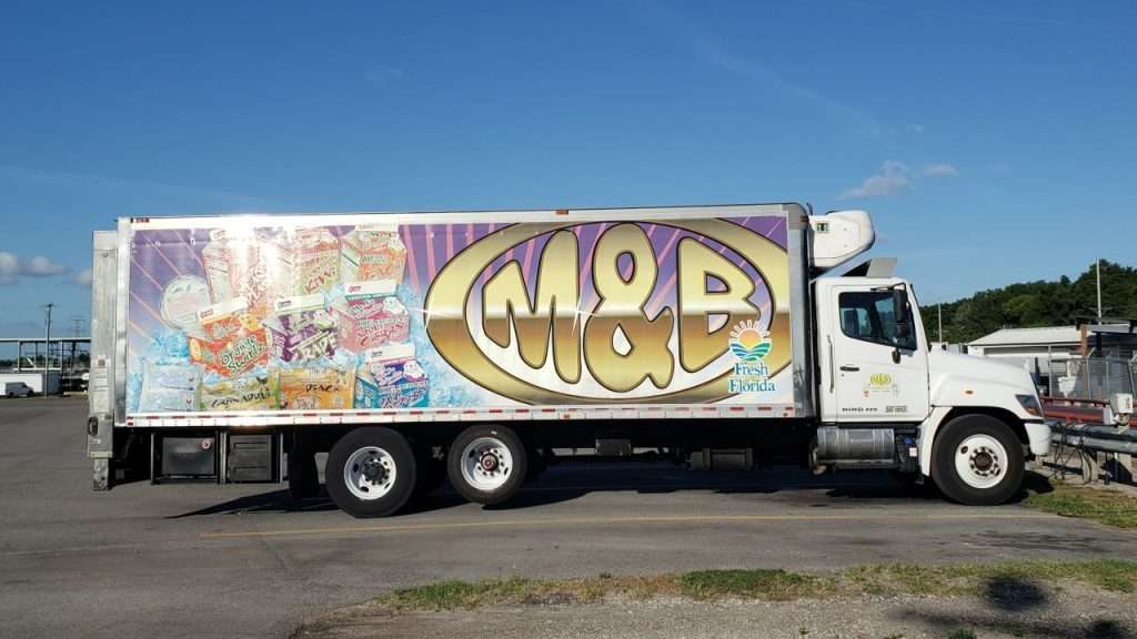 Semi-truck in parking lot with M&B Dairy graphic on the side.