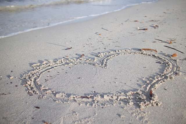 Heart traced on sand with ocean in background.