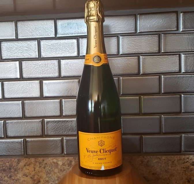 Bottle of champagne on counter with black tile in background.