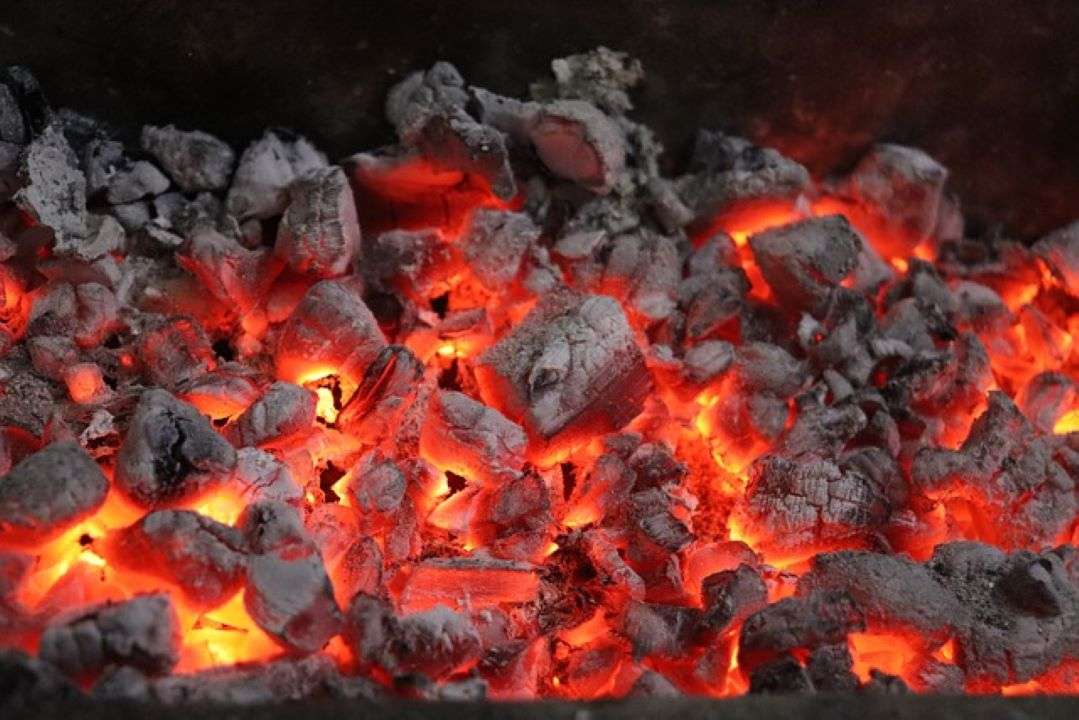 Charred coals with flame underneath.