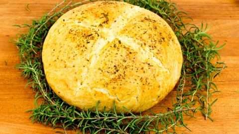 Round white bread with ring of Rosemary around it.