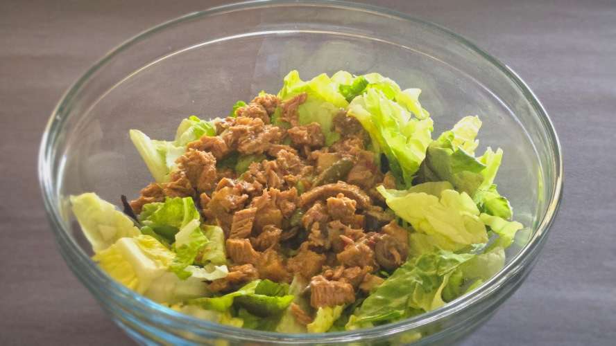 Clear class bowl with lettuce and an open can of Freshe Meal in it.