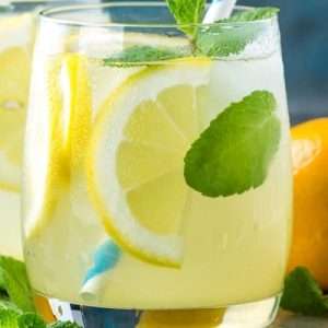 Class of lemonade with lemon wedge and mint.