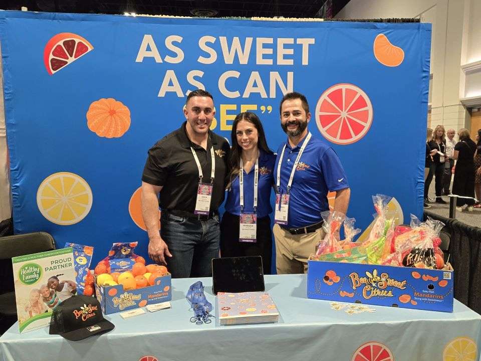 Jason Sadoian, Monique Mueller, and Sergio Rodriguez, Bee Sweet Citrus in front of display at convention center.