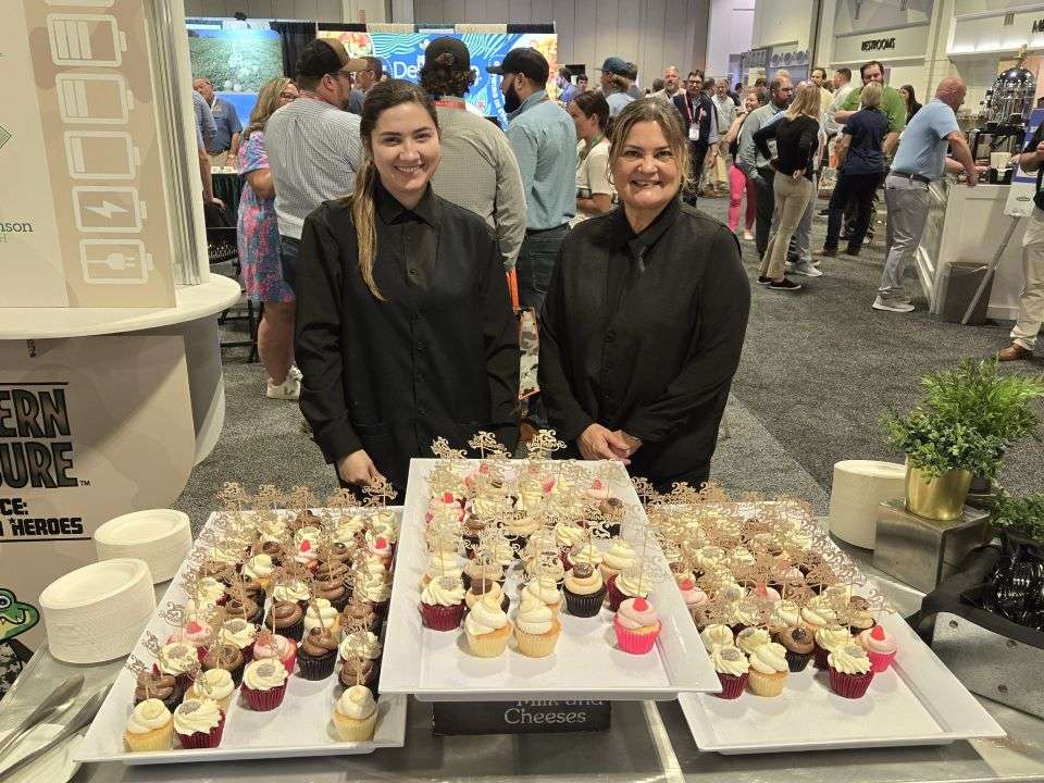 Beiniela and Brenda behind cupcake table convention center.