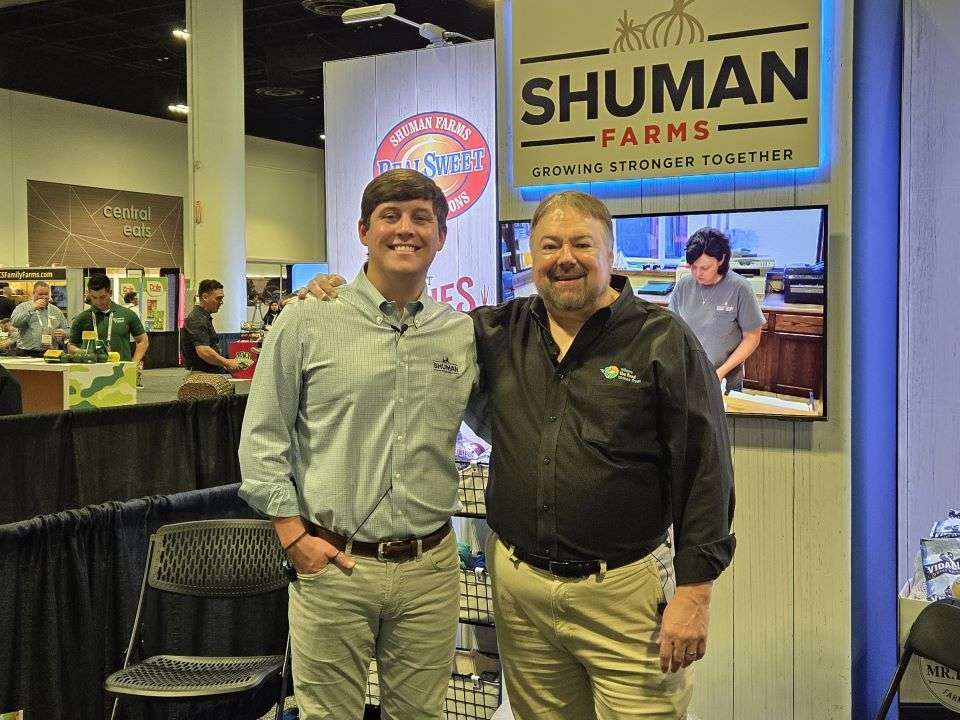 Luke Shuman, Shuman Farms, and Chip Carter in front of Shuman Farms stand in the convention center.
