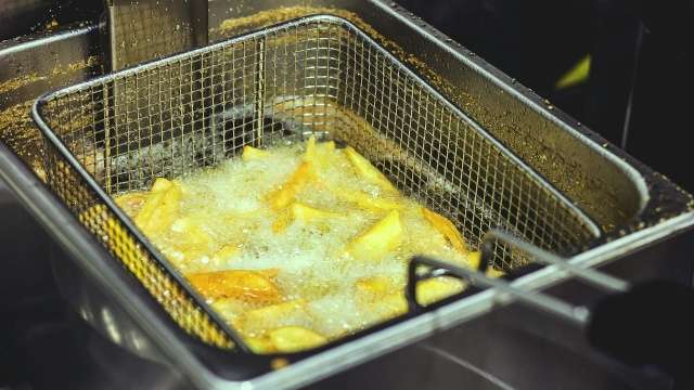 Potatoes frying in deep fryer. 