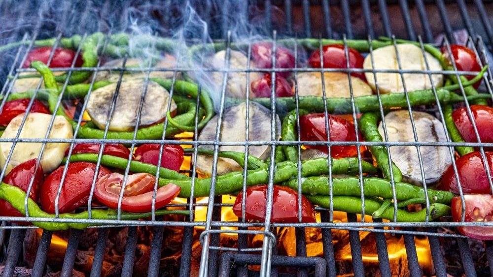 Asorted vegetables grilling over a flame. 