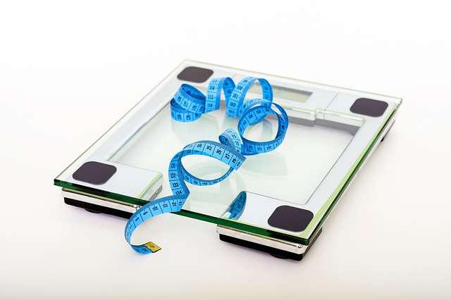 Glass scale with blue measuring tape on it.