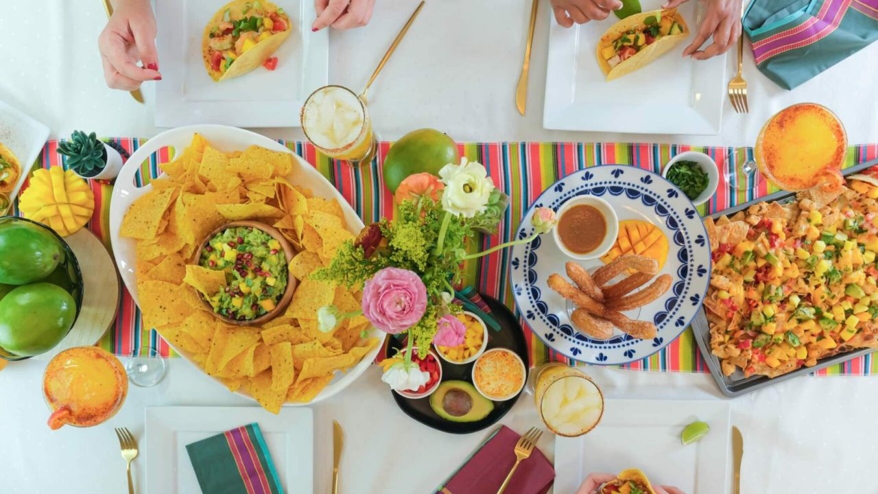 Top down view of diners eating tacos at a table.