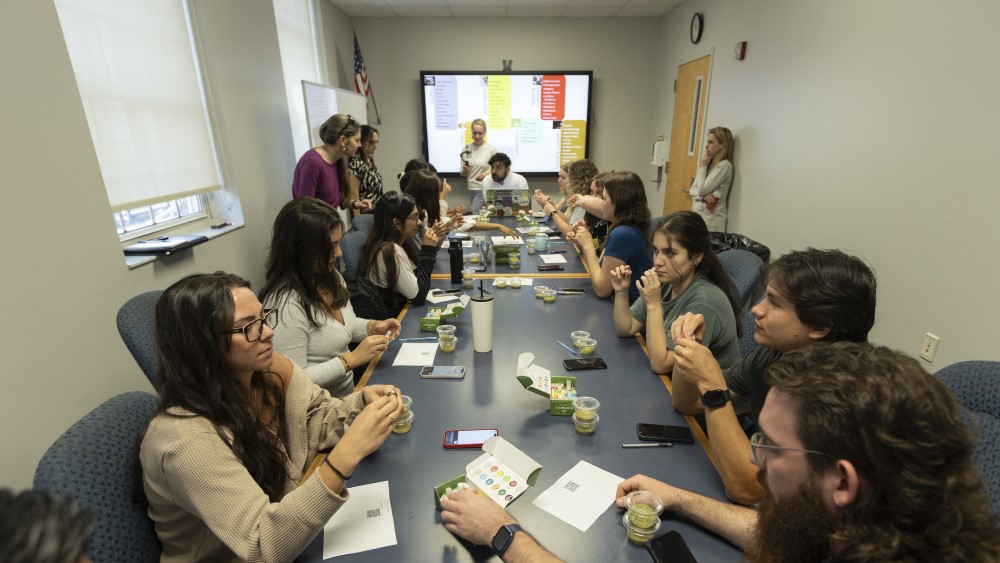UF students in a focus group sitting at a table examining hops. 