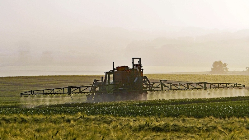 Tractor spraying pesticides in commercial field.