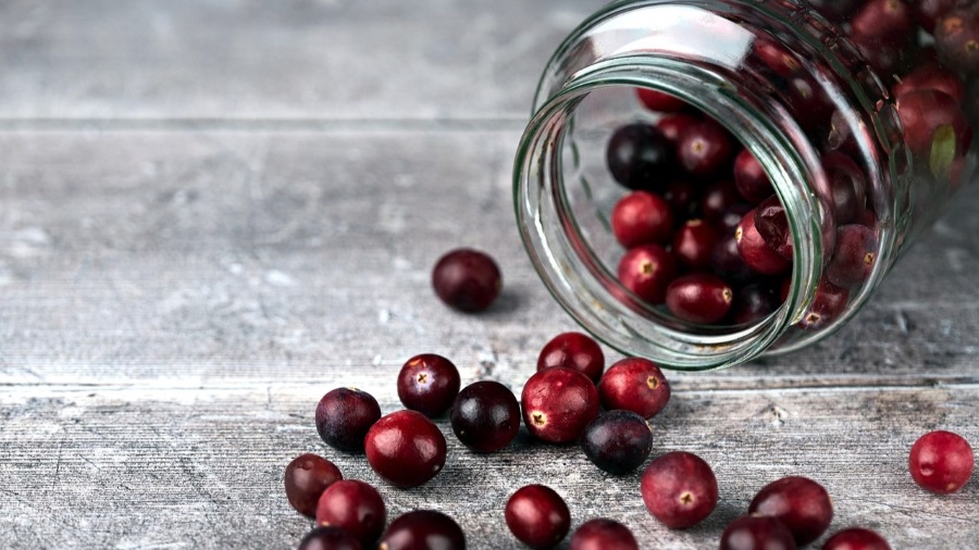 Cranberries spilling out of a mason jar. 