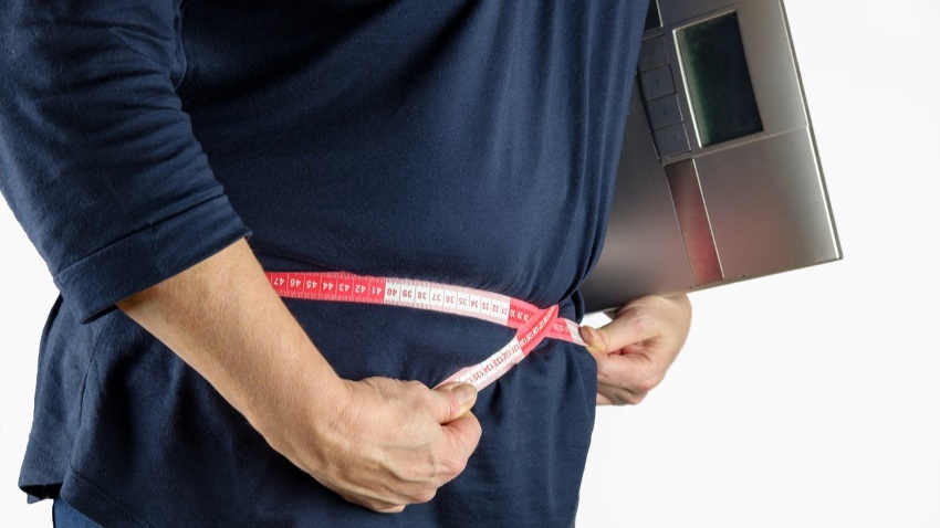 Heavy-set individual measuring waistline.