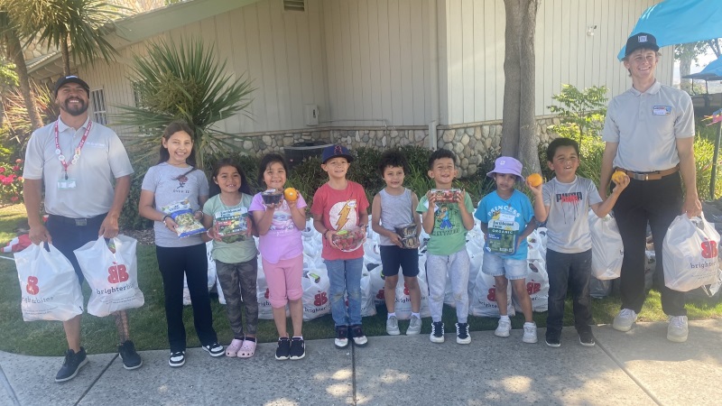 Brighter Bites reps and kids holding packages of fresh produce.