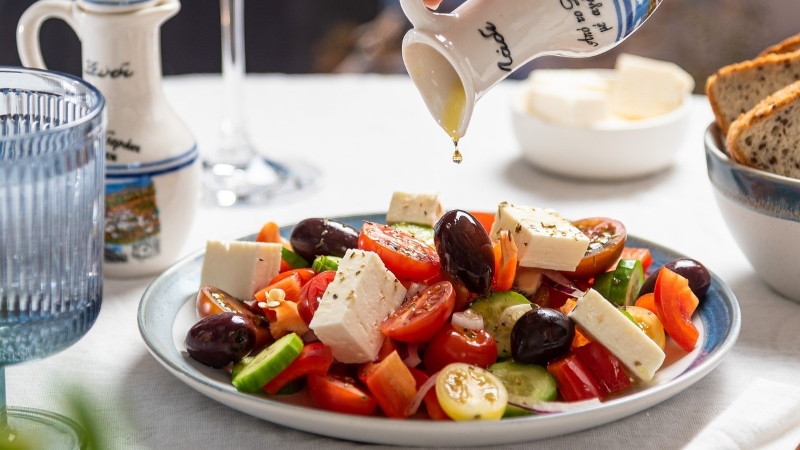 Salad with tomatoes, feta cheese, olives, cucumber and olive oil drizzle.