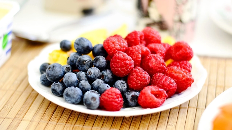 Plate of pineapple, blueberries and raspberries.