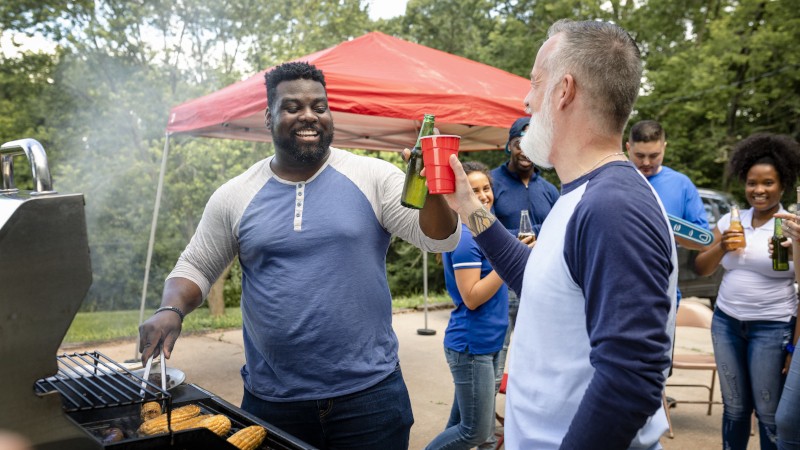 Tailgaters working food on a grill. 