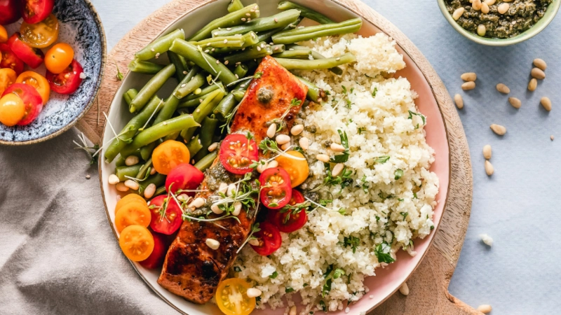 Salmon dish with vegetables and pine nuts.