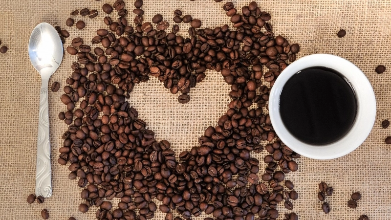 overhead shot of coffee cup and beans with a heart. 