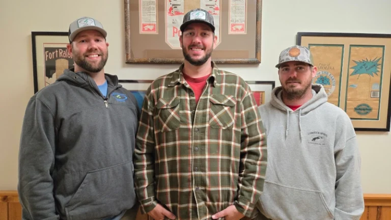 Ethan Meiggs, Austin Jennings, Scott Jennings standing in front of wall at the farms office.
